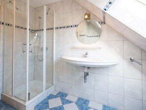 A bathroom with a glass shower enclosure, a sink, and a mirror. - Holiday Apartment Baltic Sea Breeze (Fehmarn)