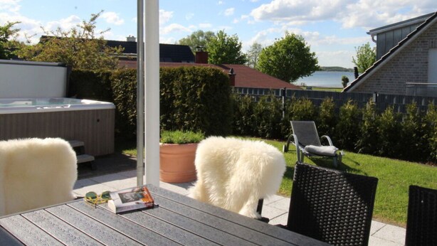 Une terrasse avec un jacuzzi, une table avec un magazine et une chaise.