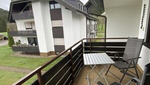 A balcony with a metal railing, a table, and two chairs. - Yvonne Comfortable Holiday Residence (Titisee-Neustadt)