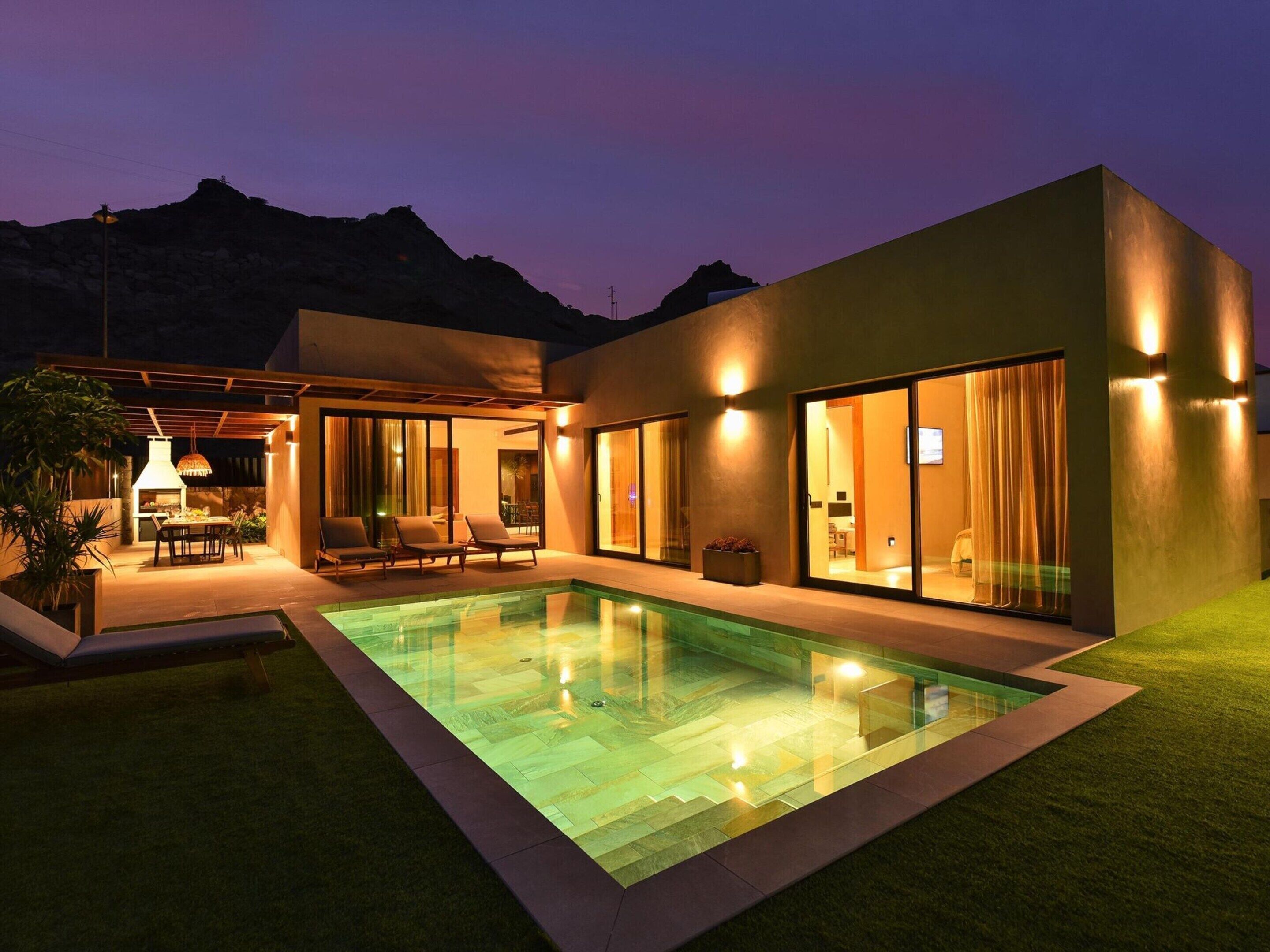 A modern house with a swimming pool, outdoor seating, and a mountain view.