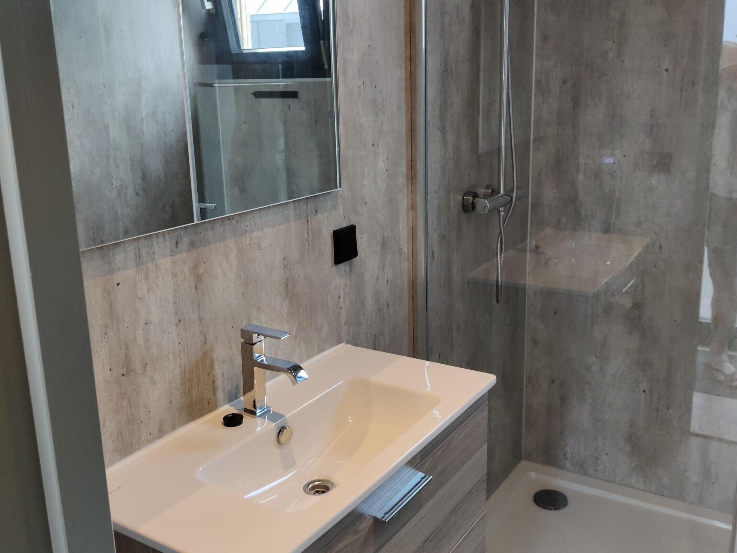 A bathroom with a white sink, a mirror, and a glass shower enclosure.