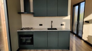Una cocina moderna con armarios oscuros, horno empotrado y estufa a gas.
