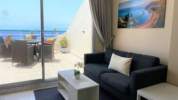 Una sala de estar moderna con un sofá, una mesa de centro y un cuadro de una playa.