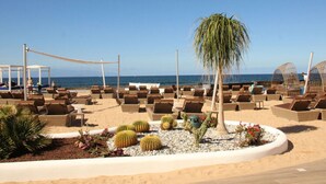 Un resort en la playa con sillas de descanso y una palmera.