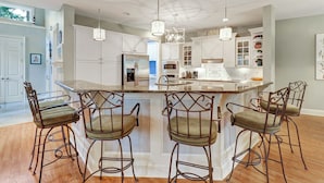 A modern kitchen with a central island, white cabinetry, and bar stools. - 2 Genoa Court at The Sea Pines Resort (Hilton Head Island)