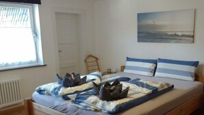 A bedroom with a wooden bed, a window with blinds, a radiator, a door, and a painting on the wall. - "ganseliesel" Comfortable Holiday Residence (Willingen)