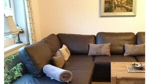 A living room with a dark brown leather sofa, a wooden coffee table, and a painting on the wall. - "ganseliesel" Comfortable Holiday Residence (Willingen)