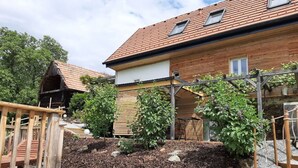 A modern house with a wooden deck, a brick garden, and a small shed. - Lovely Apartment in Rettenberg (St Andra-Hoech)