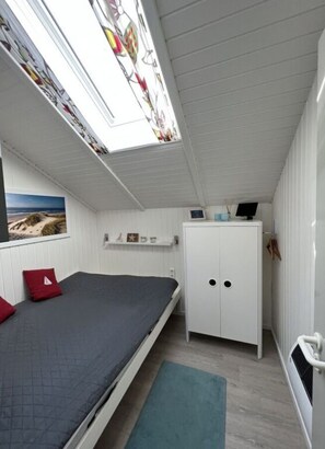 A bedroom with a skylight, a bed, a wardrobe, and a small desk. - Holnis Beach Cabin Comfortable Vacation Home (Gluecksburg)
