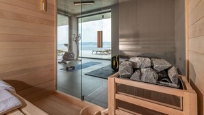A sauna room with wooden walls, a glass door, a bench, a wooden bucket, and a stone container. - Amazing Villa in Labin With Sauna, Private Pool (Rasa)