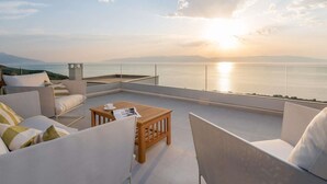 A terrace with a view of the sea during sunset, featuring a sofa set and a wooden table. - Amazing Villa in Labin With Sauna, Private Pool (Rasa)