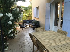 Eine Terrasse mit Holztisch und -stühlen, einer Couch und einem Blumentopf.