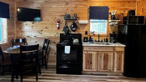 A wooden-paneled kitchen with a stove, sink, and microwave. - Cabin 2 Recreational Cozy Cabin Rentals (Sangerville)