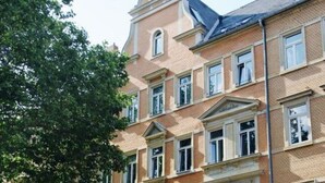 A multi-story building with a classic architectural style, featuring symmetrical windows and a prominent central tower. - Industrial Style Dresden (Dresden)