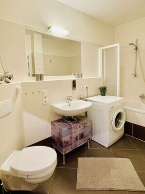 A compact bathroom with a toilet, sink, washing machine, and shower. - Industrial Style Dresden (Dresden)