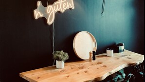 A wooden table with a neon sign that reads "h gütel!" and a hanging lamp. - Industrial Style Dresden (Dresden)