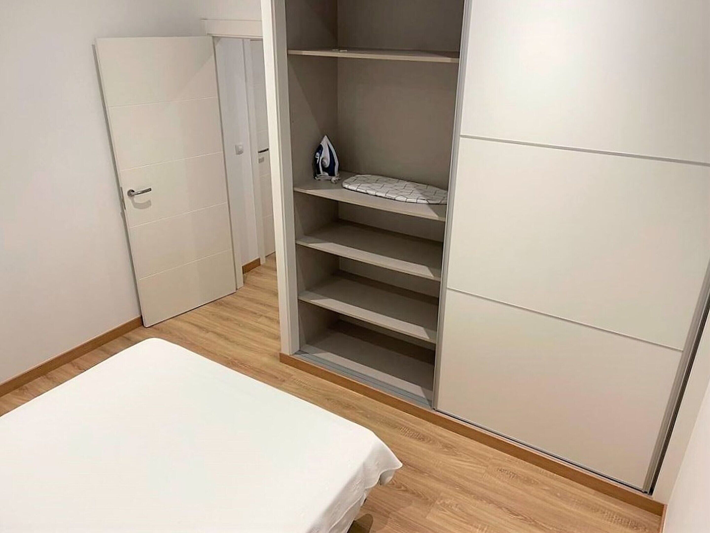 A bedroom with a bed, a wardrobe, and a built-in shelving unit.