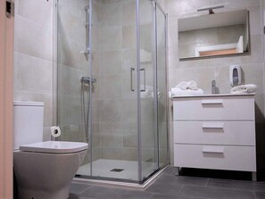 A modern bathroom with a glass-enclosed shower, a toilet, and a vanity with a mirror and towel rack. - Apartment in Ourense Near Thermal Baths (Ourense)