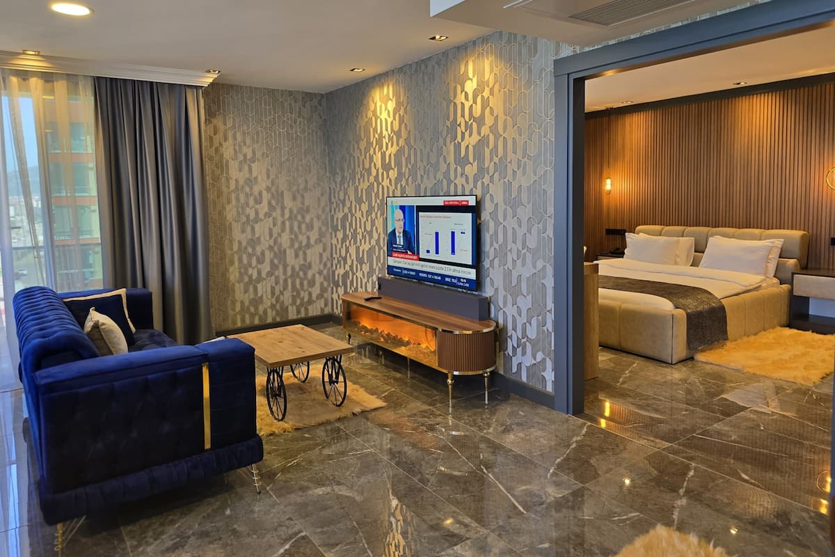 Ein modernes Hotelzimmer mit einem großen Bett, einer Sitzecke, einem Fernseher und einem Essbereich.