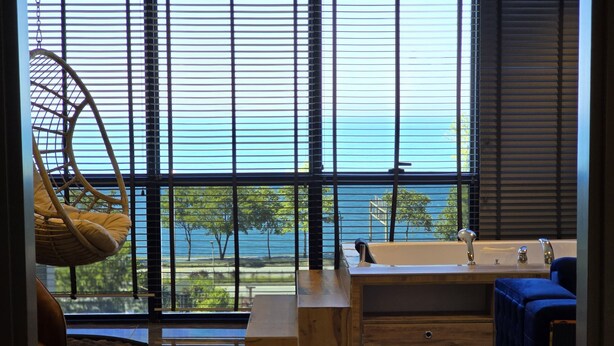 A modern bathroom with a large window, a bathtub, and a sink.