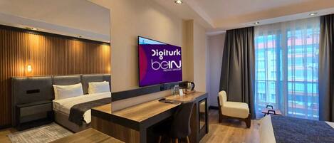 Une chambre d’hôtel moderne équipée d’un lit, d’un bureau, d’une chaise et d’un téléviseur diffusant la chaîne « Digiturk Bein ».