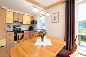Une cuisine moderne avec des meubles en bois, une table à manger et une vue sur l’extérieur.