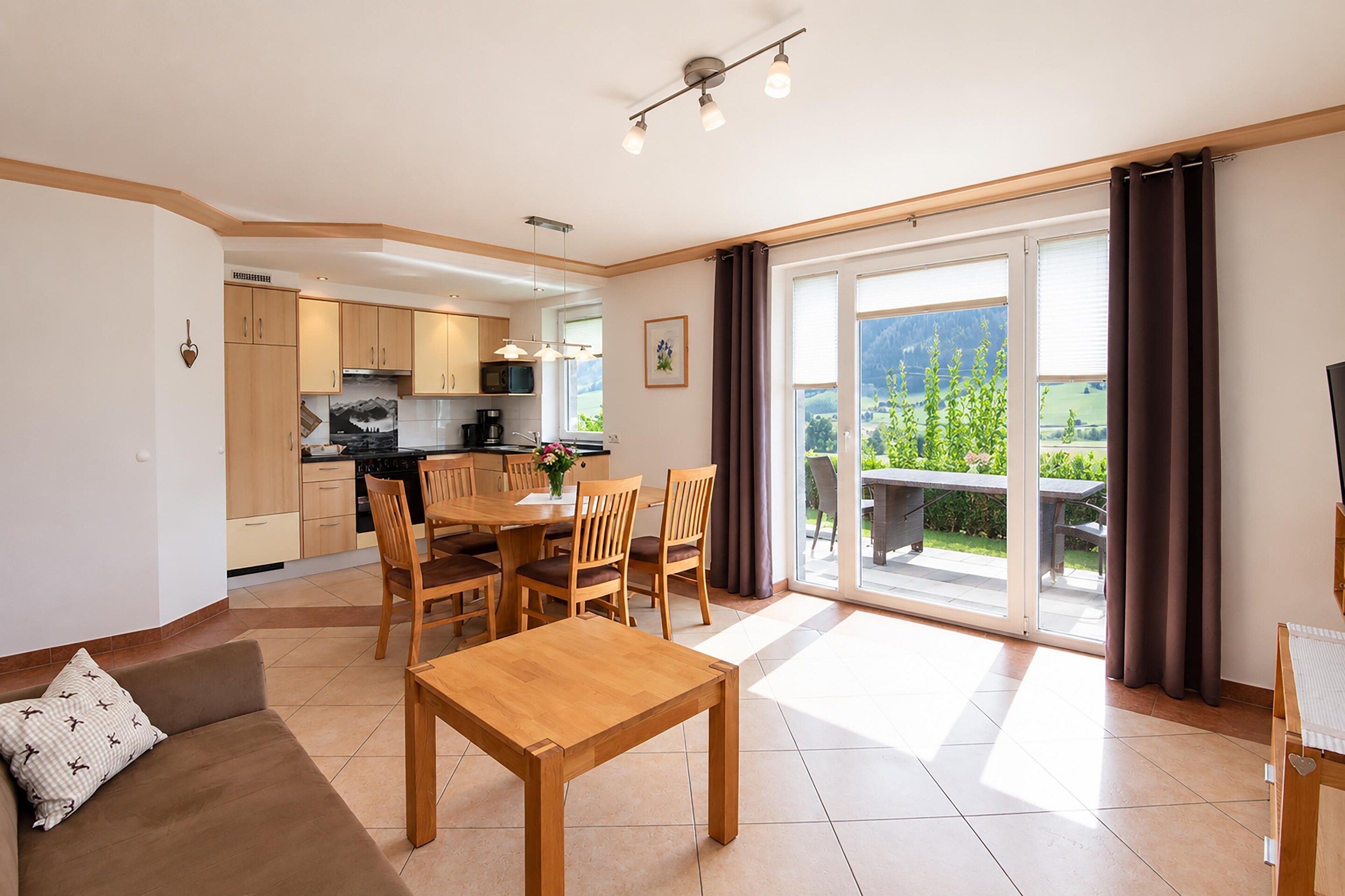 A modern apartment with a dining area, kitchen, and a balcony with a view.