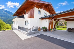 A two-story house with a wooden roof, a covered porch, and a stone wall. - Apartment in Mittersill Near ski Lift (Mittersill)