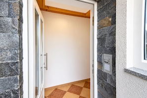 A hallway with a white door, stone walls, and a checkered floor. - Apartment in Mittersill Near ski Lift (Mittersill)