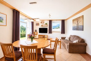 A well-lit living room with a dining area, a flat-screen TV, and a couch. - Apartment in Mittersill Near ski Lift (Mittersill)