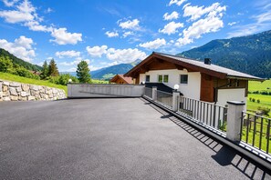 A modern chalet with a stone wall and a metal fence, set against a mountainous backdrop. - Apartment in Mittersill Near ski Lift (Mittersill)