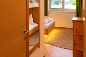 A room with a bunk bed, a single bed, a wooden wardrobe, and a window with curtains. - Apartment in Mittersill Near ski Lift (Mittersill)