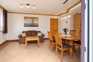 A living room with a sofa, coffee table, dining table, chairs, and a painting on the wall. - Apartment in Mittersill Near ski Lift (Mittersill)