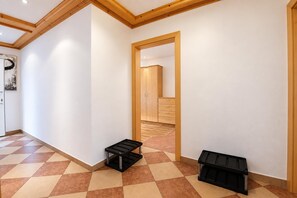 A hallway with a checkered floor, wooden ceiling beams, and a door leading to another room. - Apartment in Mittersill Near ski Lift (Mittersill)