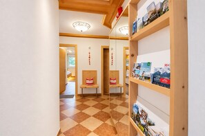 Un couloir d’hôtel avec un sol à carreaux, des murs en bois et une bibliothèque contenant des brochures de voyage.