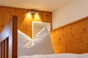 Un lit superposé en bois, avec une tête de lit, une table de chevet et un miroir.