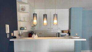 A modern kitchen with a central island, pendant lights, and bar stools.
