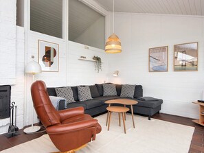 A modern living room with a leather armchair, a grey sofa, a small wooden table, and a hanging pendant light. - 4 Star Holiday Home in Aabenraa (Aabenraa)
