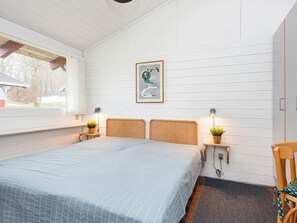 A bedroom with a bed, two bedside tables with lamps, a framed picture on the wall, and a window with a view of the outside. - 4 Star Holiday Home in Aabenraa (Aabenraa)