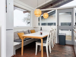 A modern kitchen with a dining area, featuring a wooden table, white chairs, and a bench with cushions. - 4 Star Holiday Home in Aabenraa (Aabenraa)