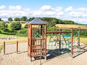 A playground with a wooden climbing structure and a netted play area. - 4 Star Holiday Home in Aabenraa (Aabenraa)