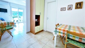 A room with two wooden chairs, a small table, a cabinet, and a door. - Holiday Home Near Spiaggia Tartaruga (Caorle)