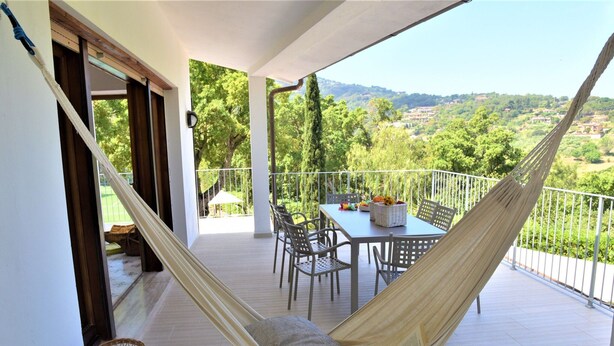 Een balkon met een hangmat, eettafel, stoelen en rieten manden.