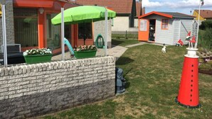 A residential backyard with a brick wall, a green umbrella, a red conical object, and a small shed. - Holiday Home Seestern 283 (Julianadorp)