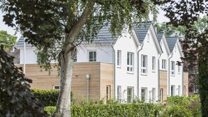 A row of modern, two-story houses with a uniform architectural style, featuring pitched roofs and a combination of white and wooden siding. - Fischer Heiligenhafen 4c (Heiligenhafen)