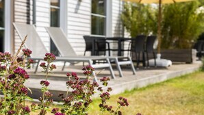 A patio with outdoor furniture, a yellow umbrella, and a house in the background. - Fischer Heiligenhafen 4c (Heiligenhafen)