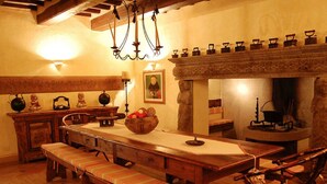 Une salle à manger traditionnelle avec une longue table en bois, des bancs et une cheminée en pierre.