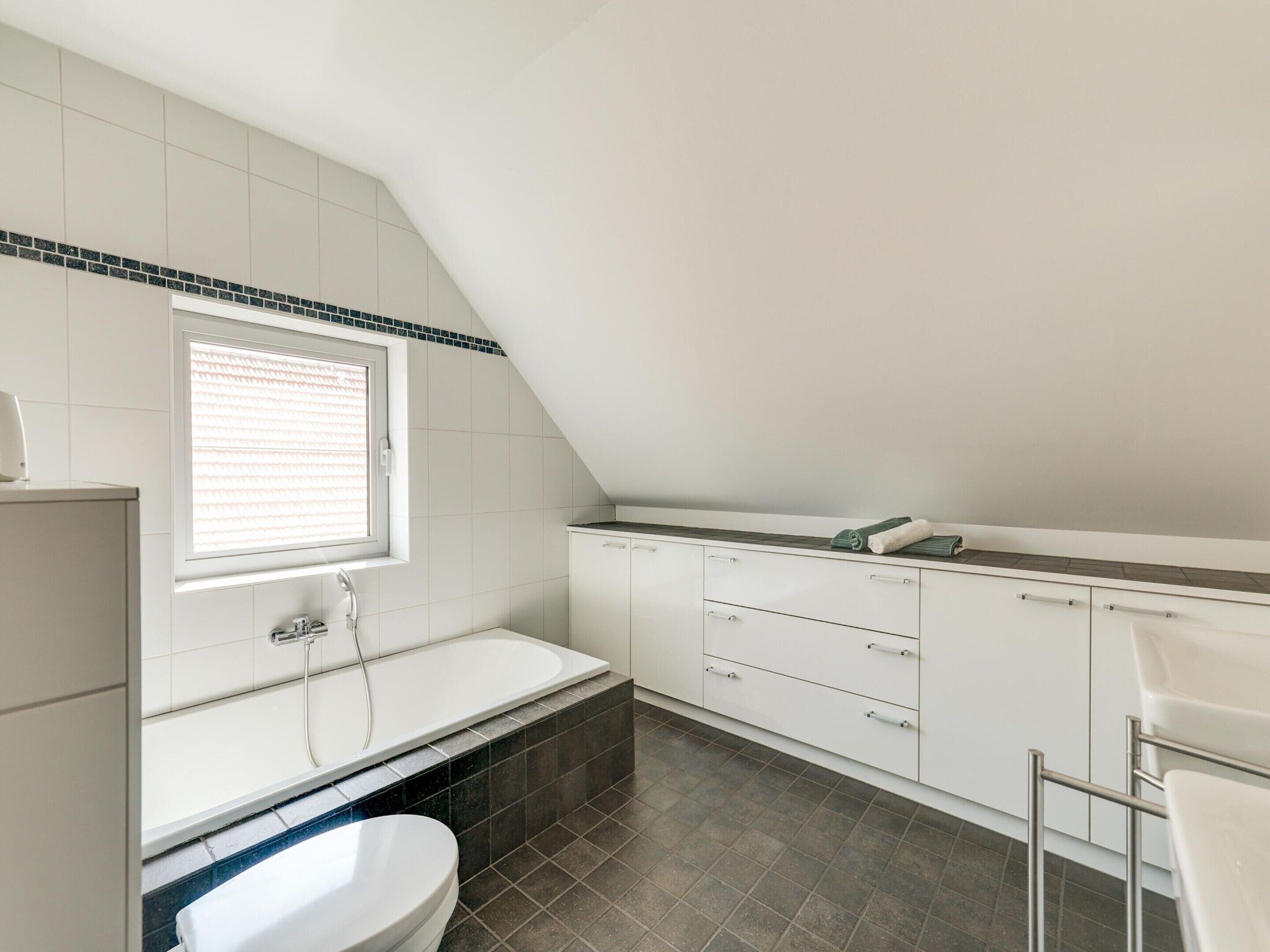 A modern bathroom with a bathtub, toilet, and vanity.