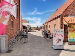 A brick building with a sign indicating it's open, bicycles parked outside, and a clear sky.