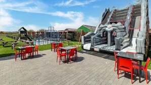 An outdoor play area with a slide, climbing structures, and picnic tables. - Cottage on Sheep Farm With Gelateria (Merksplas)